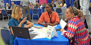 Three women delegates at Caribbean Travel Marketplace engaging in strategic discussions.