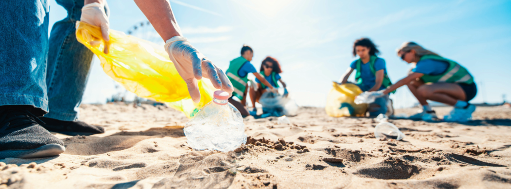Volunteers picking up plastic water bottles on a beach.