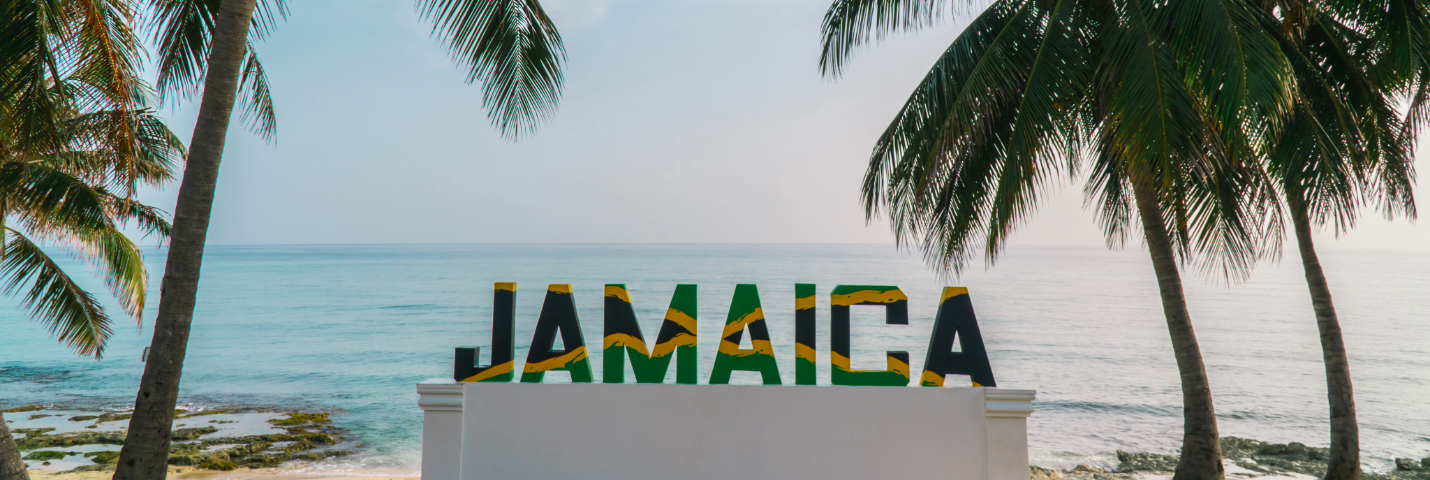 Image of Jamaica with palm trees and ocean in the background.